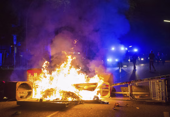 Image: Policemen stand behind a burning barricade in Hamburg.