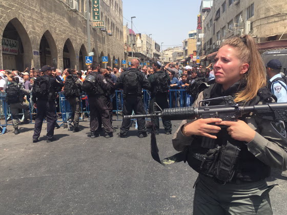 Image: About 100 Palestinians gather near a police road block in east Jerusalem.