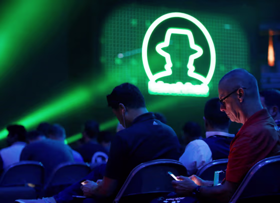Image: Attendee Don Laursen checks the conference schedule on his phone as he waits for a keynote address during the Black Hat information security conference in Las Vegas