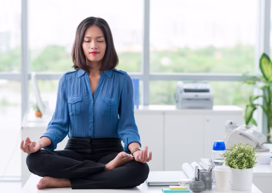 Image: A businesswoman meditates and practices yoga in her office