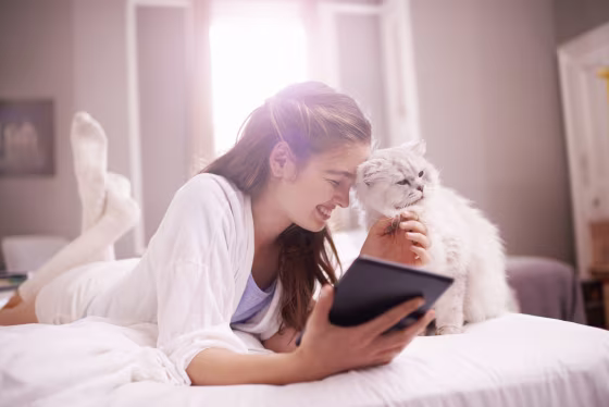 Image: A young woman lays on her bed with her cat