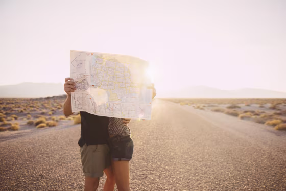 Image: couple kissing behind map on remote road