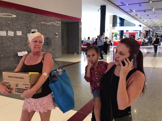 Image: Madison Gingrow, 21, holds her daughter Aleiyah, 3, and walks with her mom, Rene Farrell, 50, right, at the George R. Brown Convention Center as they try to find funds to relocate after Hurricane Harvey, Sept. 1, 2017.