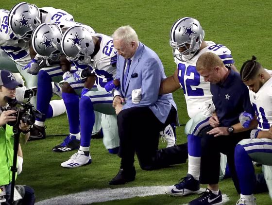 Image: The Dallas Cowboys, led by owner Jerry Jones, take a knee before the national anthem