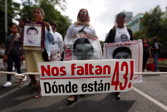 Image: A banner is seen as relatives hold posters with images of some of the 43 missing Ayotzinapa College Raul Isidro Burgos students during a march to mark the 33rd month since their disappearance, in the state of Guerrero, in Mexico City