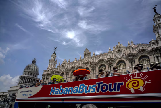Image: Tourists ride a tour bus in front of the Capitolio in Havana