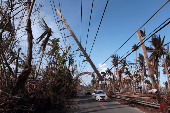 Image:Cars drive under a partially collapsed utility pole, after the island was hit by Hurricane Maria in September, in Naguabo