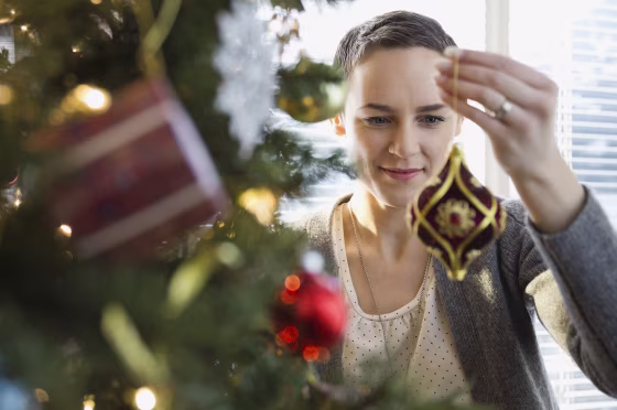 Image: A woman decorates a Christmas tree at home