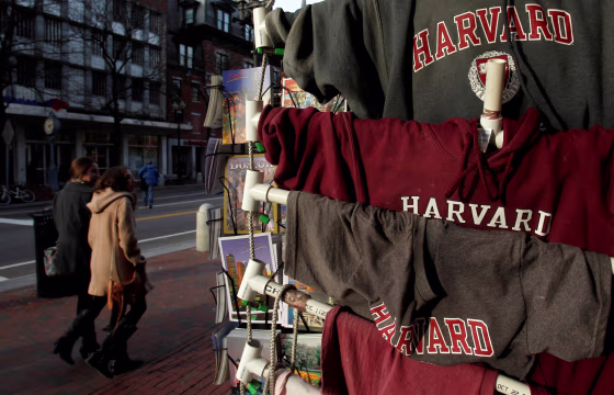 Image: People walk past Harvard University t-shirts for sale in Harvard Square in Cambridge