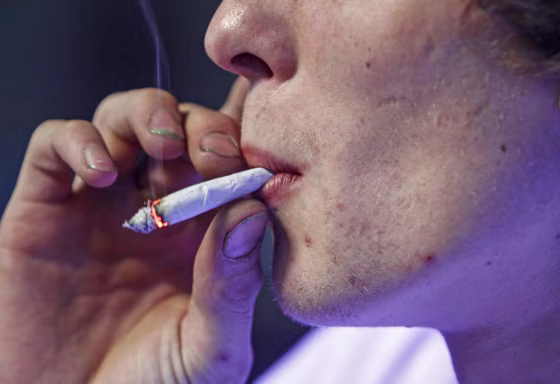 Image: Russell Diercks smokes a half marijuana and tobacco joint inside of Frankie Sports Bar and Grill in Olympia