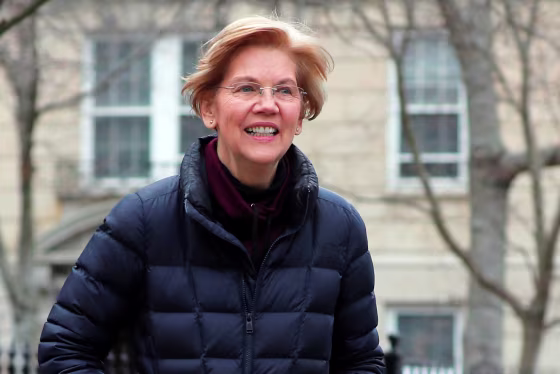 Senator Warren walks to speak to reporters outside her home in Cambridge