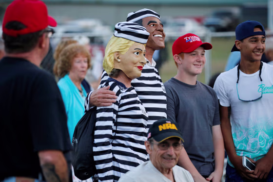 Image: People dressed as Clinton and Obama in prison jumpsuits circulate in the crowd as Trump rallies with supporters in Tallahassee, Florida