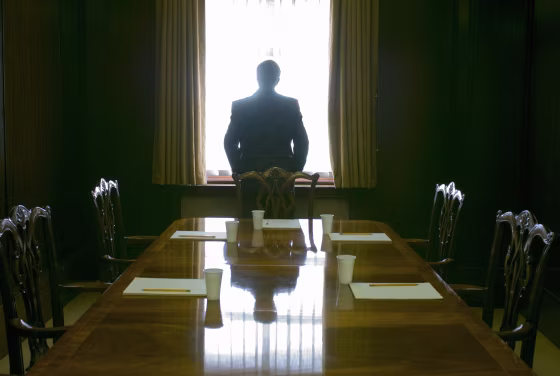 Image: A businessman looks out the window of a meeting room