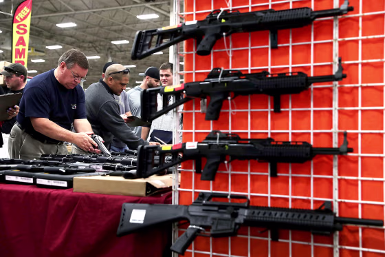 Image: Potential buyers try out guns which are displayed on an exhibitor's table during the Nation's Gun Show