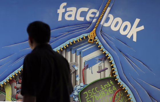 Image: A man walks past a mural in an office on the Facebook campus