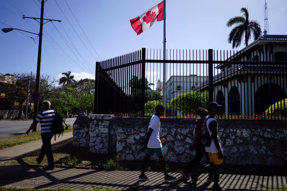 Image: People pass by the Canada's Embassy in Havana