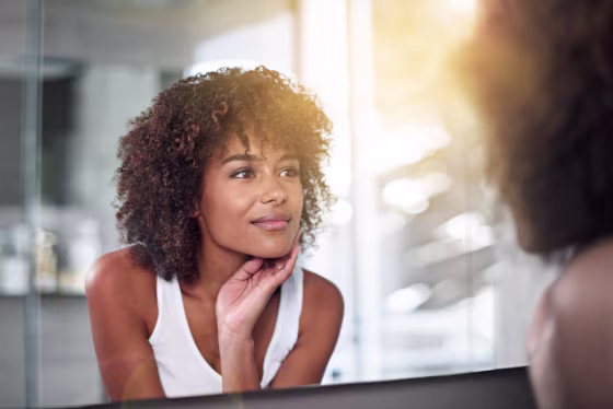 Image: A woman examines her skin in the bathroom