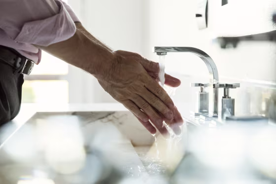 Image: A man washes his hands in a bathroom sink