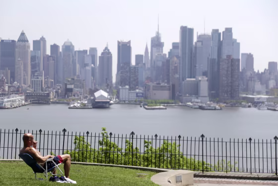Image: A man enjoys the sunshine and the New York City skyline from a park