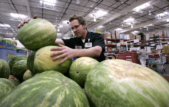 Image: A Costco produce stocker stacks watermelons on May 29, 2008.