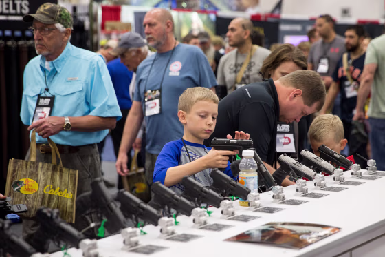 Image: A young boy inspects a firearm in an exhibit hall at the NRA's annual convention on May 5, 2018 in Dallas.