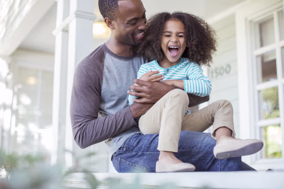 Image: Father tickling daughter on porch