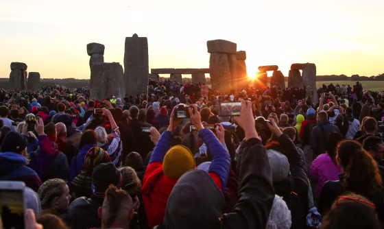 Image: Revelers watch the sunrise as they welcome the summer solstice