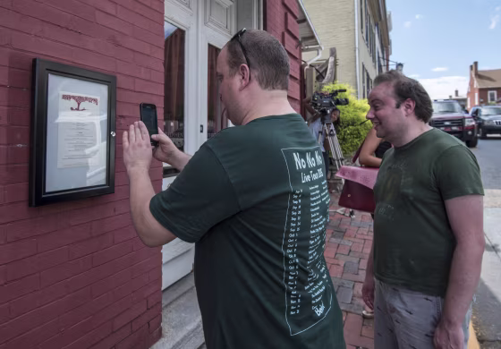 A passerby takes a photo of the menu outside of the Red Hen Restaurant on Saturday in Lexington, Virginia.