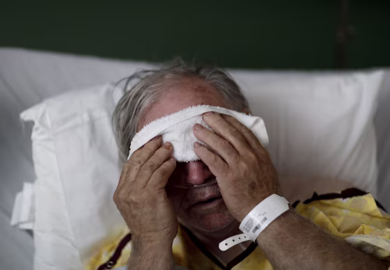 Image: A man places a cold compress on his forehead while battling the flu