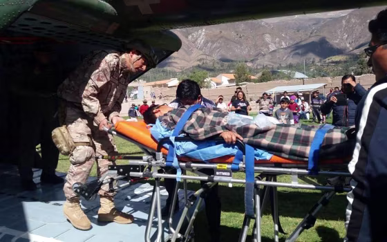 Image: A person is transported to a helicopter after eating contaminated food at a funeral in the Peruvian Andes, in Ayacucho