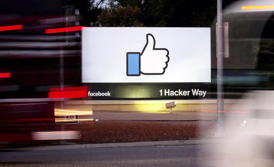 Image: The entrance sign to Facebook headquarters is seen through two moving buses in Menlo Park