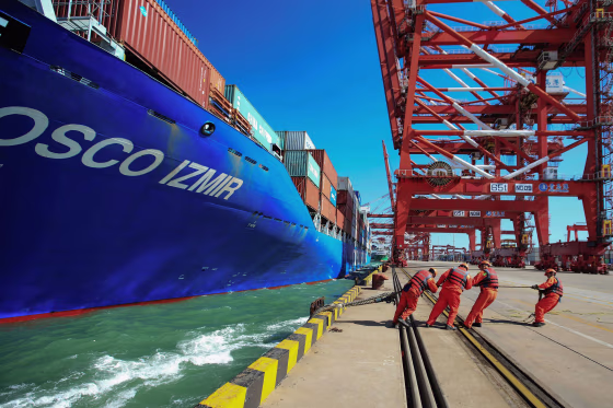 Image: Workers pull a line from a cargo ship as it prepares to berth at a port in Qingdao in China's eastern Shandong province