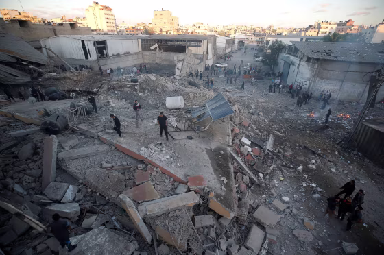 Image: Palestinians inspect the scene of an Israeli air strike on a building in Gaza City