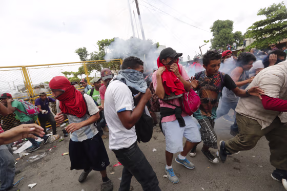Image: Migrants break the fence between Guatemala and Mexico and fight police