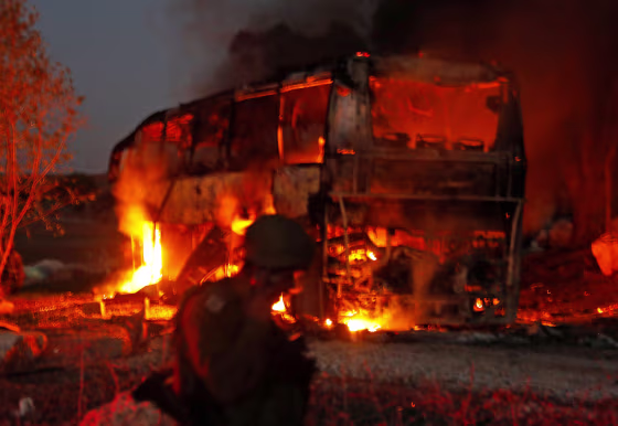 Image: Israeli security forces and firefighters gather near a bus set ablaze after it was hit by a rocket fired from the Palestinian enclave