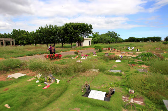 Image: People walk past graves at Eden Gardens cemetery in Maracaibo