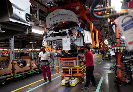 Image: General Motors assembly workers connect a battery pack underneath a Chevrolet Bolt EV in Lake Orion, Michigan, on March 19, 2018.