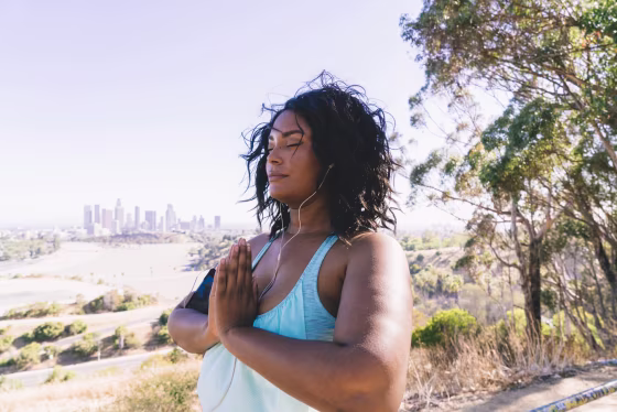 Woman with eyes closed doing prayer position exercise against clear sky