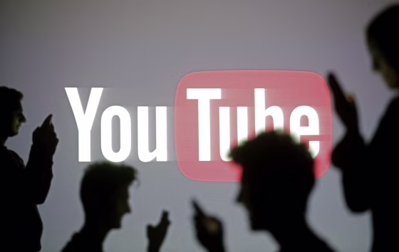 Image: Silhouette of people on mobile phones in front a YouTube sign