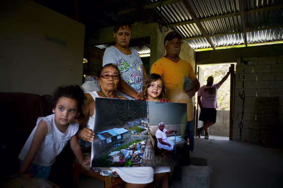 Image: Juana Sostre Vazquez holds a photo of her taken after Hurricane Maria destroyed her home on May 26, 2018.