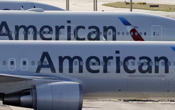 Image: A pair of American Airlines jets are shown parked on an airport apron