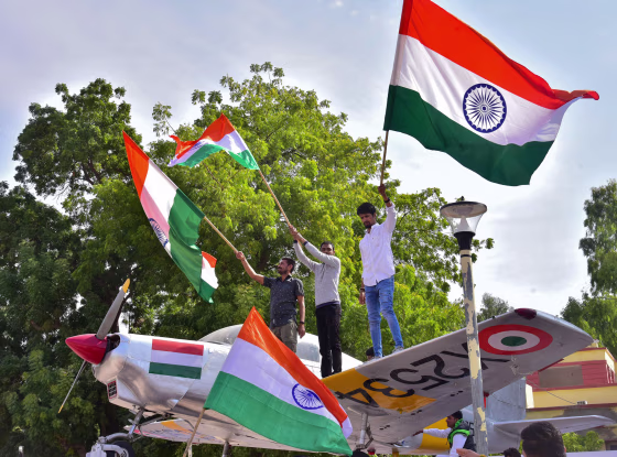 Image: Indian residents hold flags on a model of a military plane to celebrate the Indian Air Force (IAF) strike launched on a Jaish-e-Mohammad (JeM) camp at Balakot