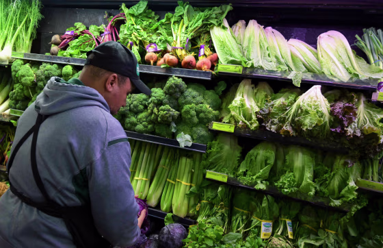 A produce worker stocks shelves near romaine lettuce at a Whole Foods supermarket in Washington on Nov. 20, 2018.