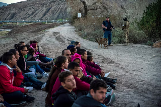 Image: Jeff Allen, a property owner, stands with a Constitutional Patriots militia member near a group of Brazilian migrants who just crossed the into the United States from Mexico in Sunland Park, on March 20, 2019.