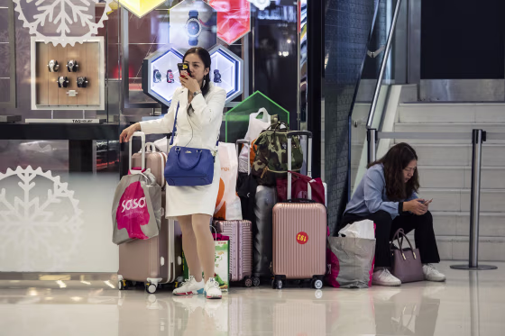 Image: Shoppers stand with suitcases and shopping bags inside Harbour City shopping mall in Hong Kong, China