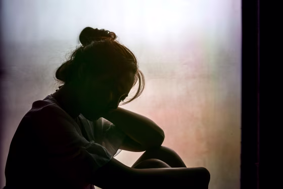 Image: Depressed or grieving woman near window