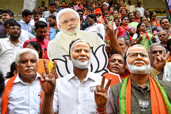 Image: Indian supporters and party workers of Bharatiya Janata Party (BJP) wear masks of Indian Prime Minister Narendra Modi and flash victory signs as they celebrate on the vote results day for India's general election in Bangalore