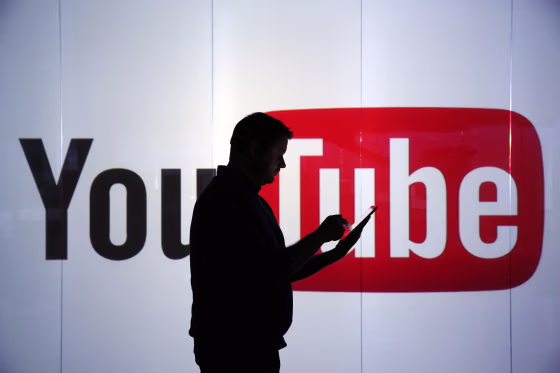 Image: A man stands in front of YouTube's logo at an office in London