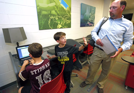 Image: Graham Stidham asks his father, East Webster High School Assistant Principal Corey Stidham, to use the internet as his brother, Miles, finishes a game at the school in Maben, Mississippi, on May 8. 2019.