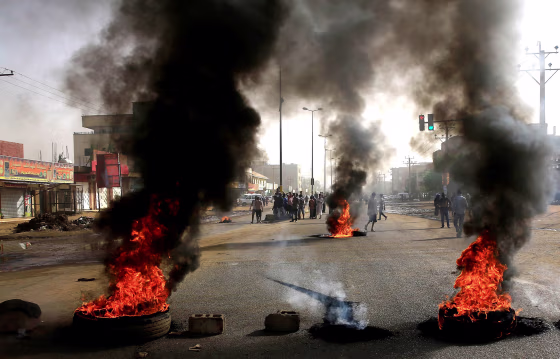 Image: Sudanese protesters use burning tyres to erect a barricade on a street, demanding that the country's Transitional Military Council hand over power to civilians, in Khartoum
